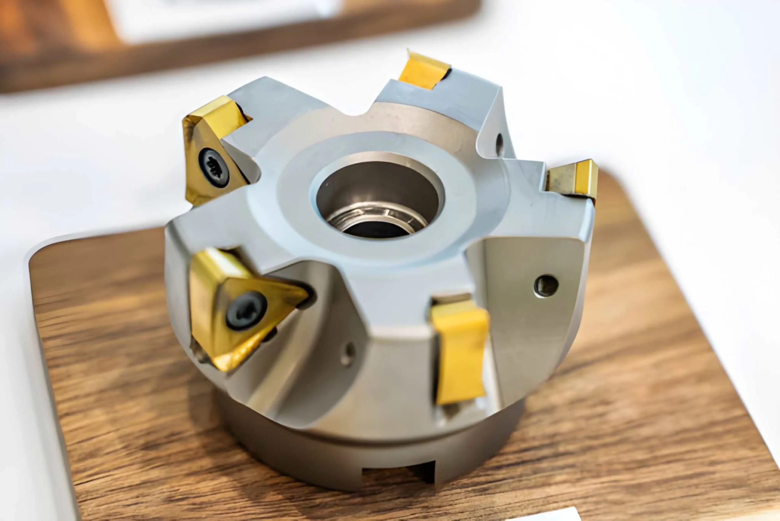 A high-precision industrial face milling cutter tool with five gold-colored indexable carbide inserts secured by screws into a silver steel body.